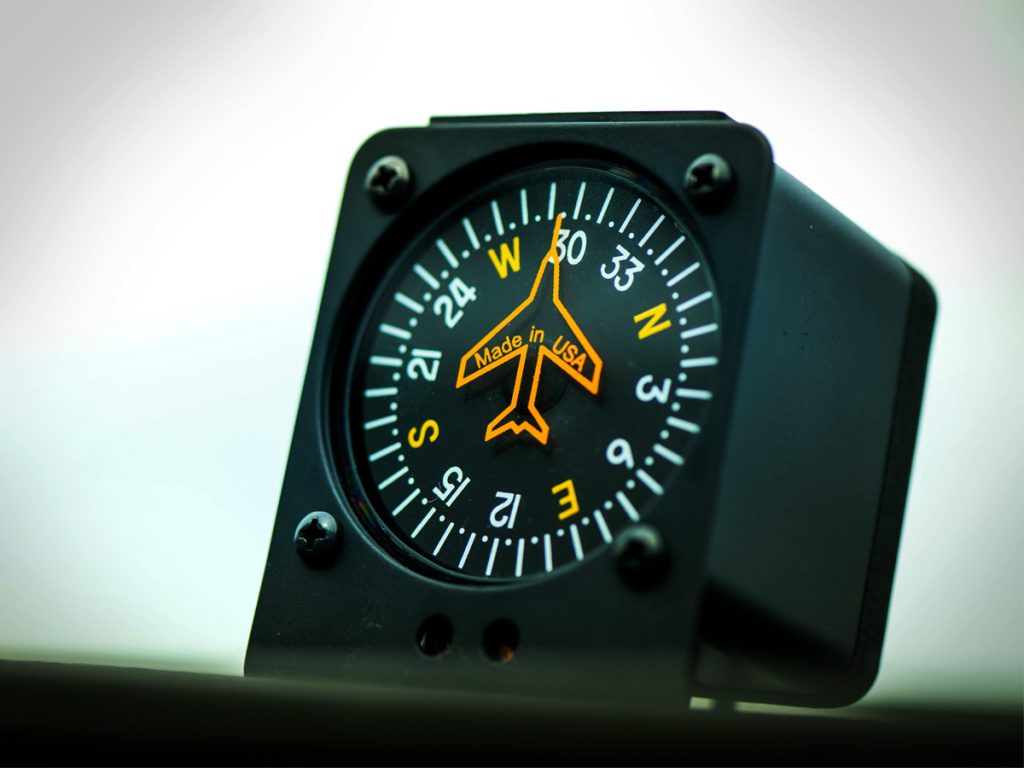 Traditional magnetic compass on top of airplane dashboard